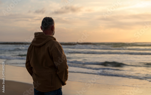 Bearded Man relaxing alone on the seaside on hot sunny day at sunset. Travel Lifestyle concept