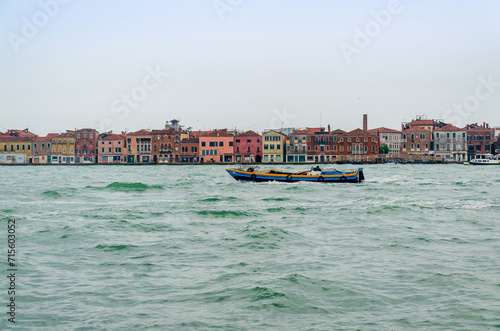 Part of a cityscape of Venice, Italy, with a boat in blue Adriatic sea