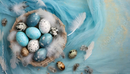 Niebiesko-białe wielkanocne tło z pisankami w koszyku, piórami i ktaniną