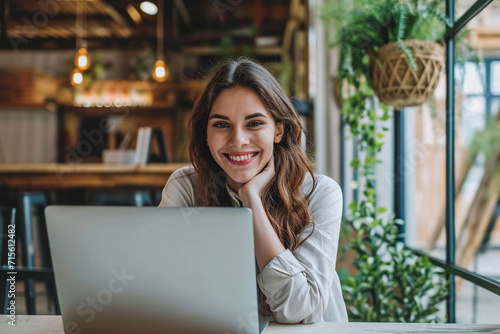 Young business woman working in laptop and smiling looking at camera