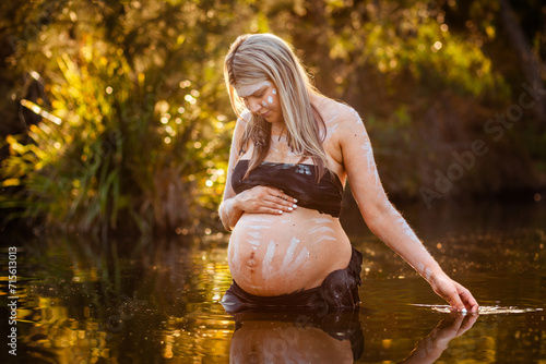 Peaceful scene with pregnant aboriginal woman in still water with reflection photo