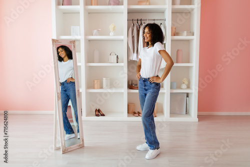 Confident woman posing in mirror wearing jeans and white t-shirt