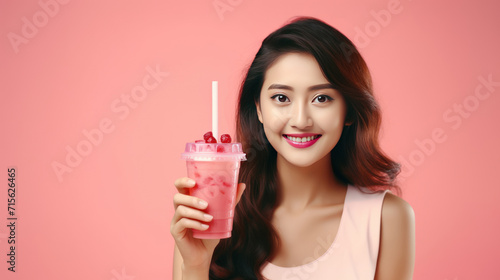 Cheerful asian woman drink ice cocoa with straw thirsty refreshment looking camera on pink background. Portrait excited girl holding ice beverage in cup plastic use straw drinking relax over isolated. photo