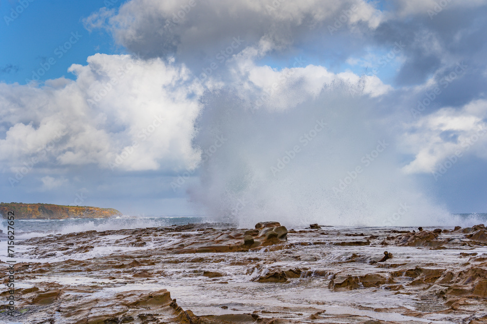 Waves crashing and flowing over a rocky ledge along a rugged coastline Waves crashing and flowing over a rocky ledge along a rugged coastline