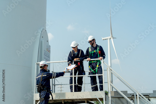 One of professional technican worker give the document to his coworker stand in base of windmill or wind turbine. photo