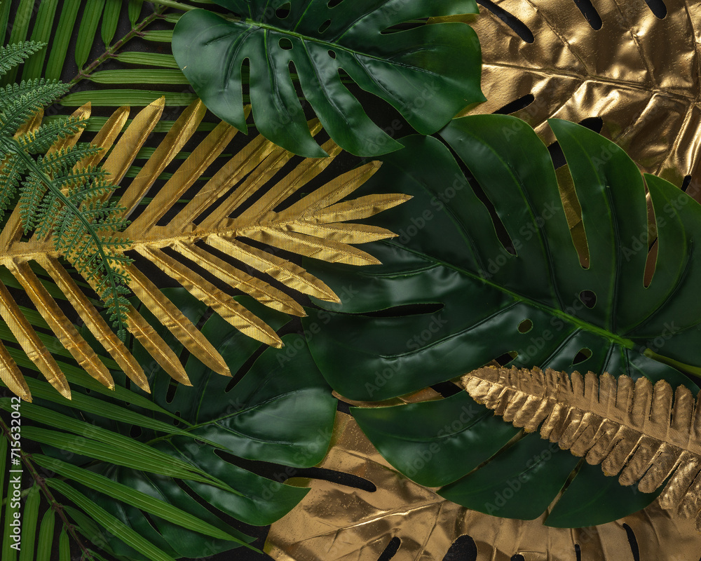 Obraz premium Creative layout with gold and green tropical palm leaves on black background. Minimal summer abstract pattern.