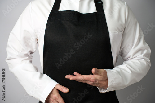 Male chef wearing apron and pointing with hand