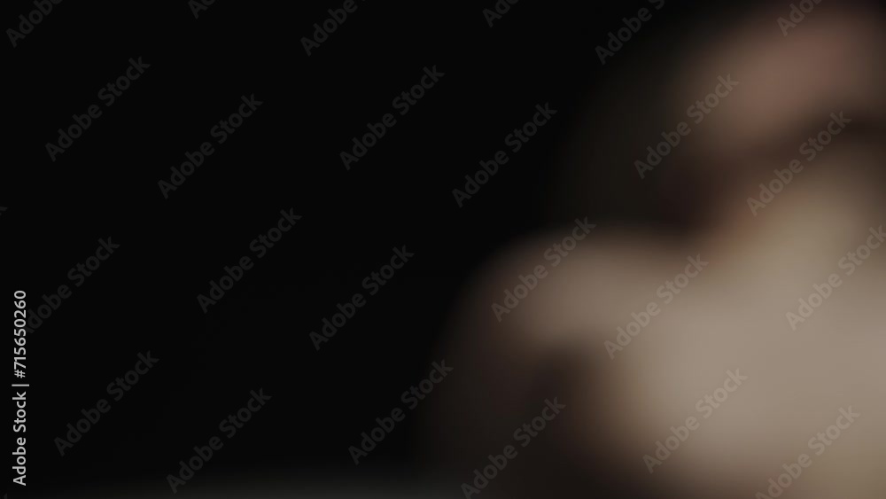 Portrait of male model on the black background in spotlight. Handsome man silhouette laying on the floor at the camera. Slow motion. Portrait of male model on the black background in spotlight. Handsome man silhouette laying on the floor at the camera. Slow motion.