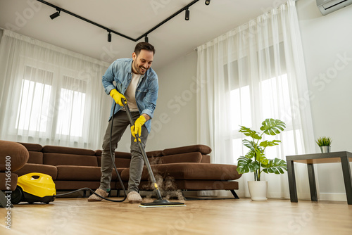 Young man using vacuum cleaner at home photo