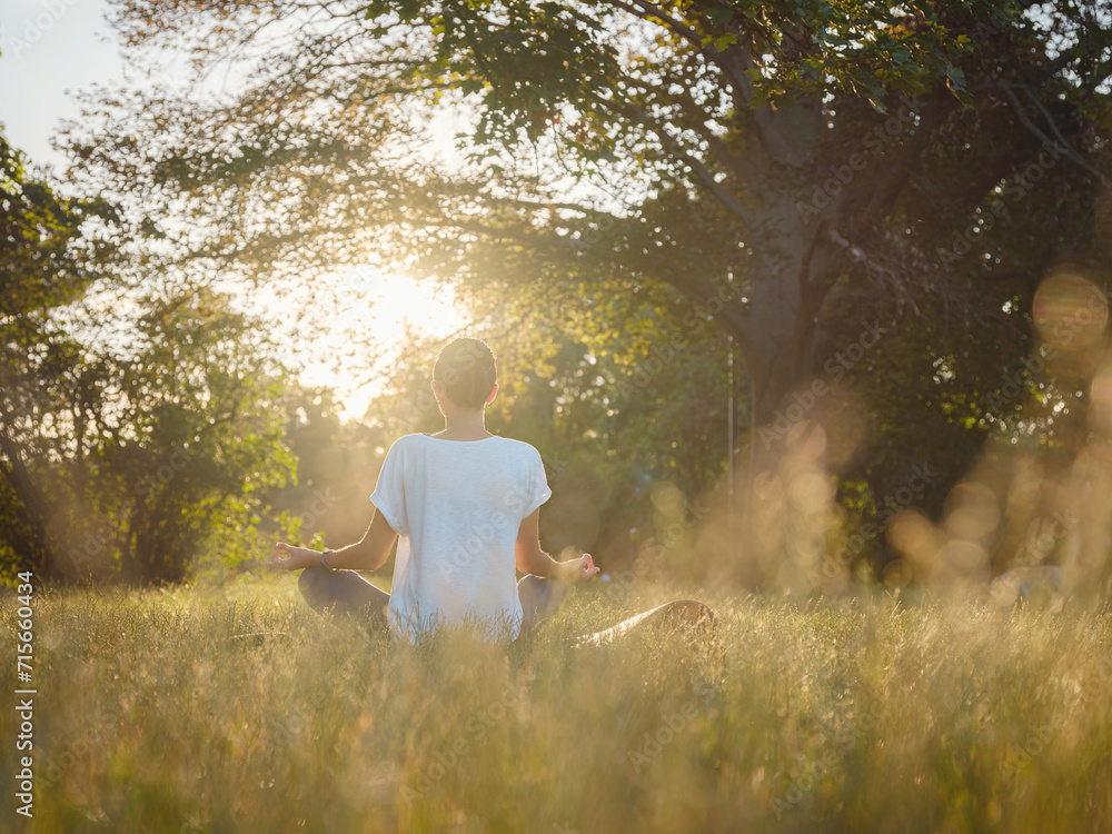 Young asian woman doing meditation in morning or evening at park, healthy woman relaxing and practicing yoga at city park. Mindfulness, destress, Healthy habits and balance concept Young asian woman doing meditation in morning or evening at park, healthy woman relaxing and practicing yoga at city park. Mindfulness, destress, Healthy habits and balance concept