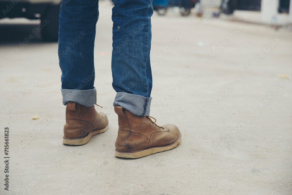 Legs of Lonely man wearing jeans and leather boots walking along the path strewn with rocks. Travel Concept.