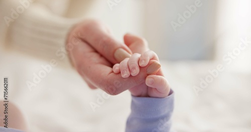 Sleeping, family and holding hands with baby on bed for bonding, love and relationship with infant. Adorable, care and closeup of parent with newborn for support, dreaming and protection at home photo