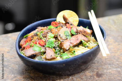 close up view of asian salad nam tok with noodles and beef