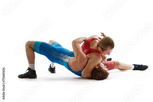 Greco-Roman, freestyle wrestling. Two sportsman, fighting in red and blue uniform in action against white studio background. Concept of fair wrestling, championship, win competition. photo