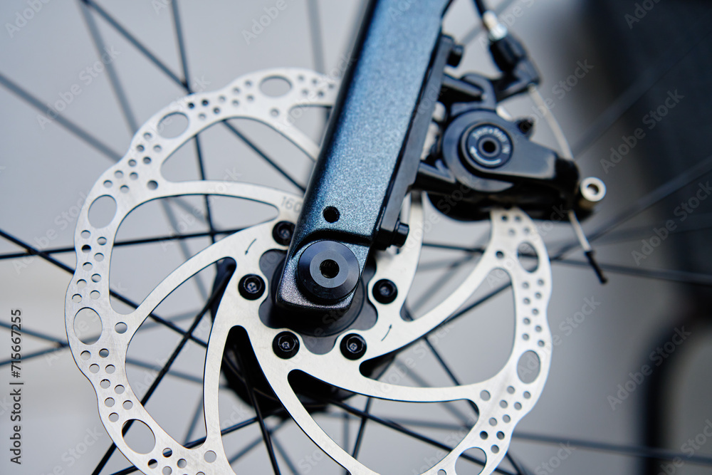 Part of the bicycle's braking system. Grey metal brake disc and brake pads on road bike, close up. Part of the bicycle's braking system. Grey metal brake disc and brake pads on road bike, close up.