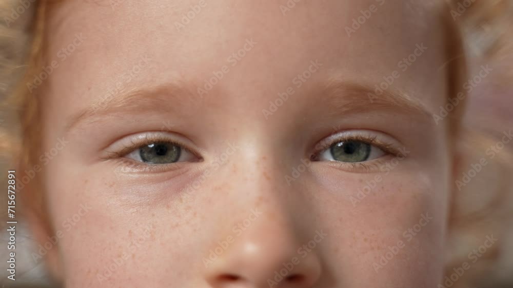 Close up of little ginger girl face blinking with beautiful grey eyes looking the camera. Kid's sight with freckles. Slow motion. High quality 4k footage Close up of little ginger girl face blinking with beautiful grey eyes looking the camera. Kid's sight with freckles. Slow motion. High quality 4k footage