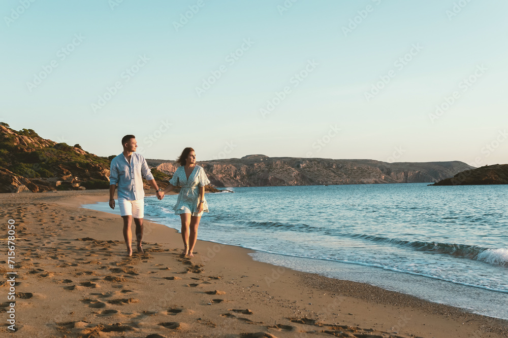 Happy couple is walking on the beach during sunset or sunrise. Summer vacations.