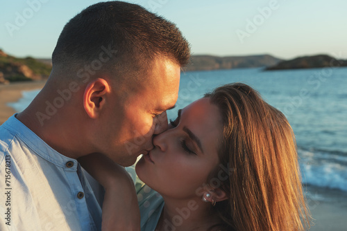 Happy couple in love kissing on the beach during sunset or sunrise. Love concept.