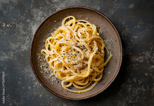 Cacio e Pepe spaghetti on a plate, top view, isolated on a dark marble table