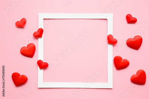Bright red textile hearts on light pink table background. Pastel color. Love concept. Top view. Empty place for lovely, emotional, sentimental text, quote or sayings in white frame. Closeup.