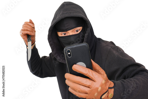 A man wearing a hoodie, a balaclava and gloves is holding a smartphone and a knife photo