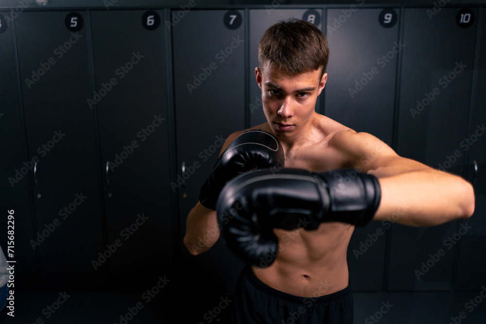portrait of a young boy boxer in boxing gloves practicing his punches in the gym before training