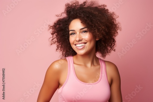 Joyful young woman with curly hair smiling on a pink background