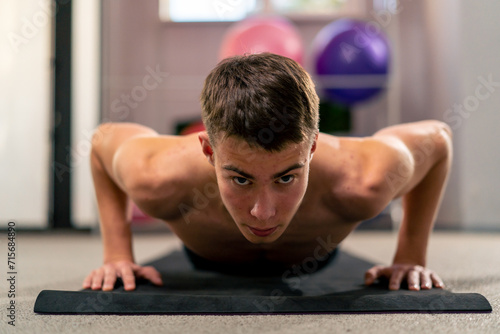 young guy doing push-ups on the mat in the gym doing exercises for the muscles of the arms