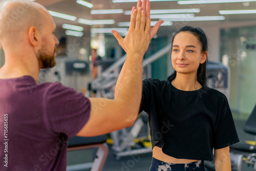 girl fitness trainer and bodybuilder in the gym give each other a high five after a group workout