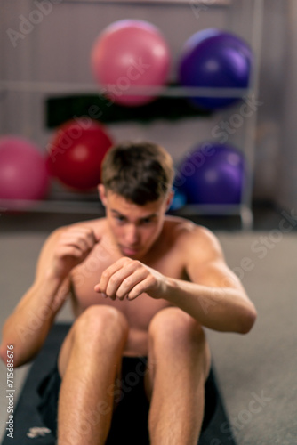 Fototapeta Naklejka Na Ścianę i Meble -  young guy concentrates on doing abs exercises on the mat in the gym practicing kicks sport