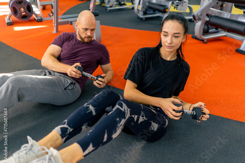girl fitness trainer and bodybuilder doing exercises with dumbbells in gym group training for abs