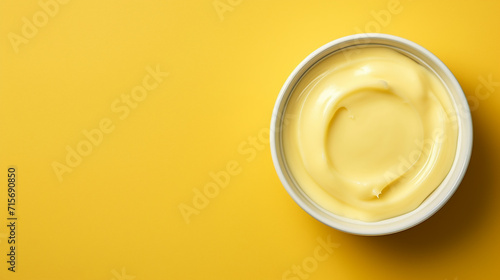 Bowl with melted butter or cheese on yellow background, top view. Dairy products