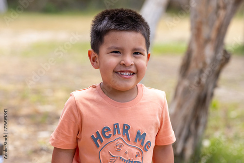 head and shoulders of little boy with black hair smiling and squinting