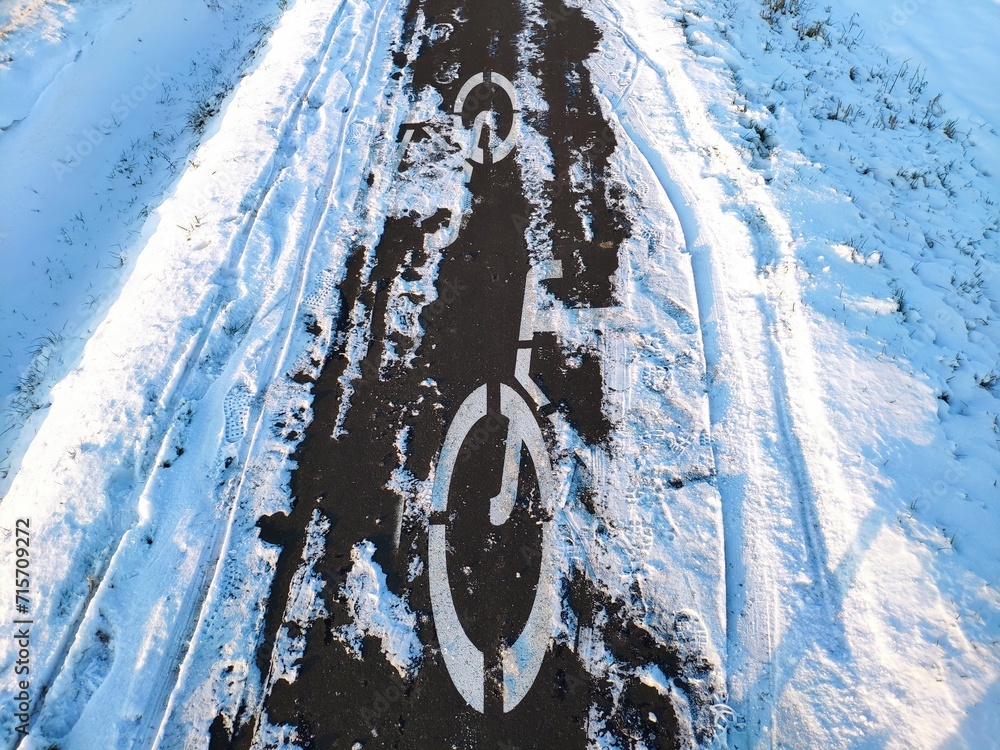 Snow cleaning problems in winter: bike path (cycle path) cleaned by a snowplow from ice with a hardly visible sign