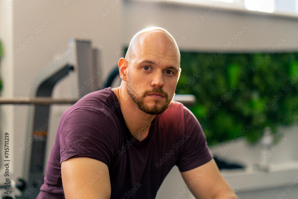Fototapeta premium portrait of a bald bearded pumped-up sportsman bodybuilder in the gym after training