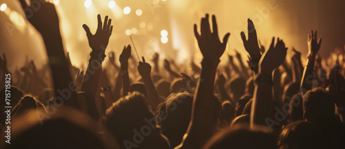 The electric energy of a rock concert captured as fans raise their hands in unison under the golden stage lights