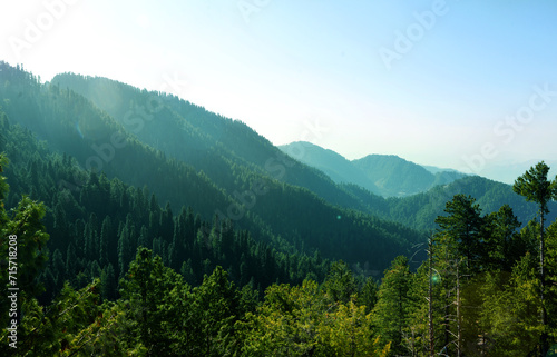 A Beautiful Mountains landscape view with green trees and sunlight from the side, nature wallpaper. Green and blue natural color morning time mountains backdrop
