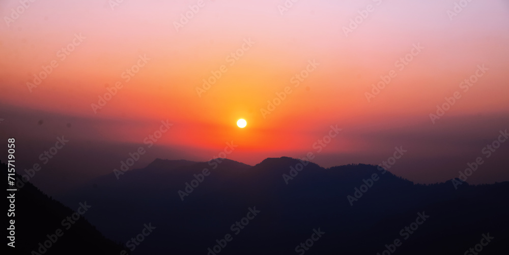 Sunset view in cinematic colors with mountains and sun setting behind, landscape wallpaper. Winter sunset view backdrop