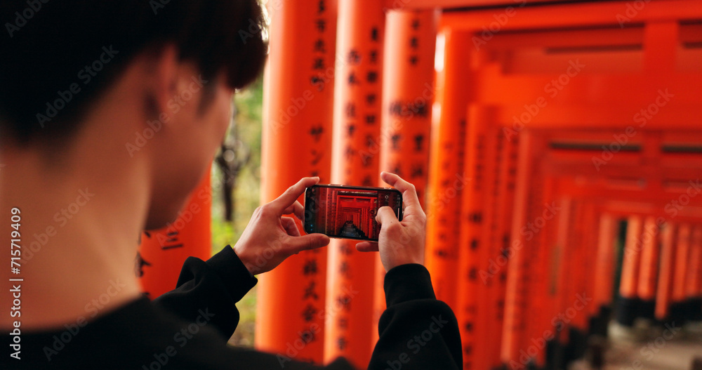 Obraz premium Phone, man and picture of torii gates on vacation, holiday trip or travel for tourism. Smartphone, hands and closeup photography of Fushimi inari-taisha in Kyoto Japan on mobile technology outdoor