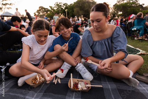 brother and sisters sharing waffles from a food truck at the carols photo