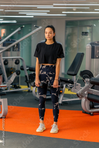 young girl in sportswear in the gym doing exercises with dumbbells training a healthy lifestyle