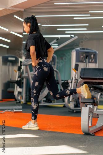 young girl in sportswear in the gym doing squats during fitness training healthy beautiful body