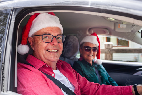 Grandparents arriving in car at Christmastime wearing Santa hats photo