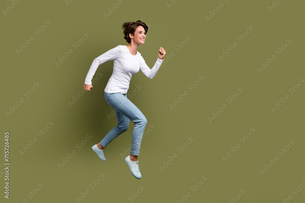 Full size photo of attractive young woman running fast shopping excited dressed stylish white clothes isolated on khaki color background Full size photo of attractive young woman running fast shopping excited dressed stylish white clothes isolated on khaki color background