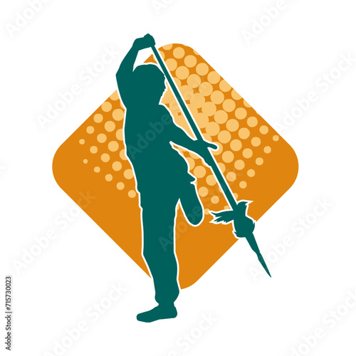 Silhouette of a wushu martial artist in action pose with a spear weapon. Silhouette of a fighter carrying a spear weapon.