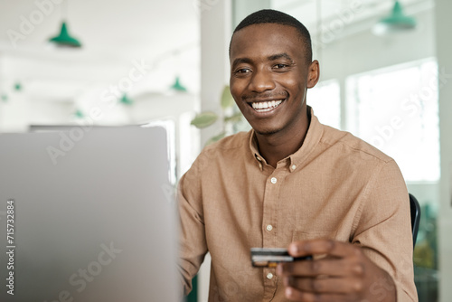 Smiling African businessman online shopping at his office desk photo