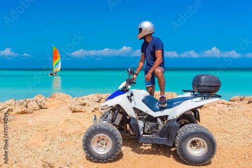 ATV driver. Quad bike rider on seashore. Guy drives ATV. Tourist with quad bike admires ocean. ATV driver at tourist resort. quad bike man at sunny seacoast. Mediterranean sea. Cyprus island photo