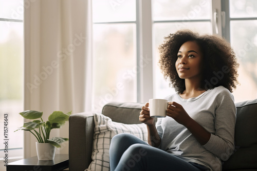 African American woman drinking coffee sitting on sofa at home photo