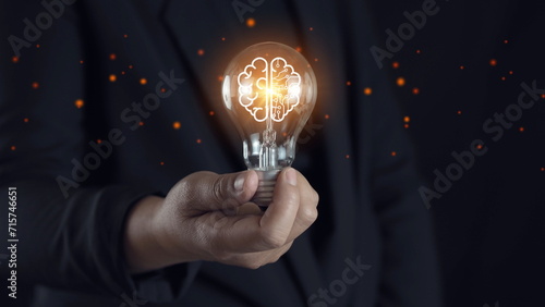 Businessman holding glowing lightbulb and human icon thinking with copy space for creative thinking idea and problem solving concept.