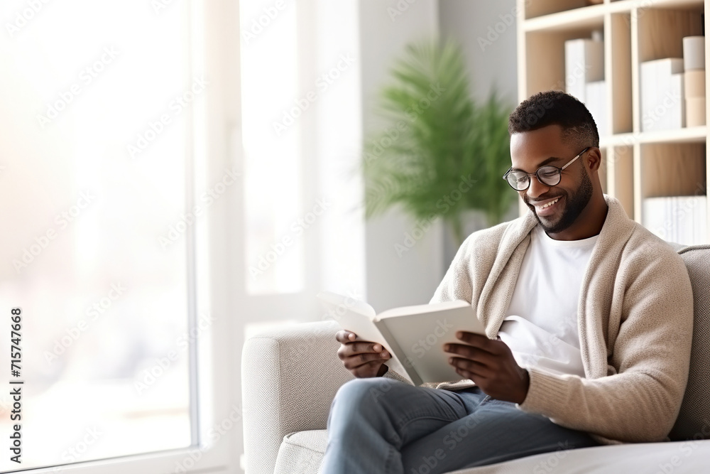 Pensive relaxed African American man reading a book at home, drinking coffee sitting on the couch. Copy space Pensive relaxed African American man reading a book at home, drinking coffee sitting on the couch. Copy space